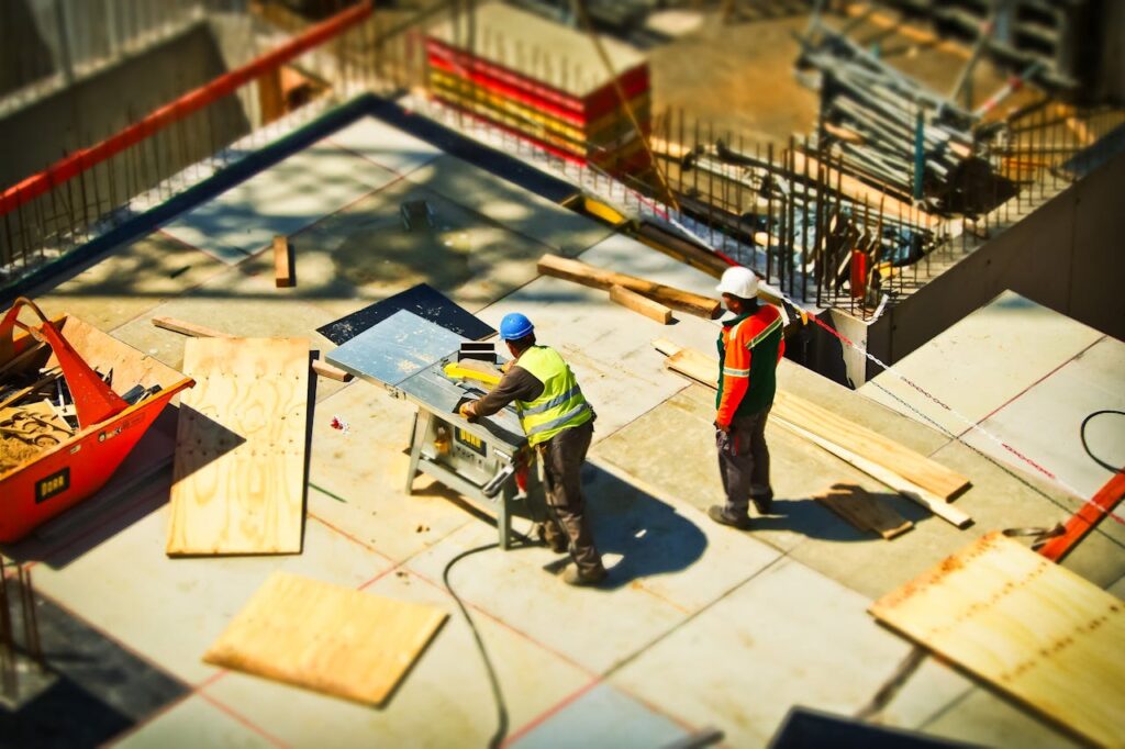 construction-site-build-construction-work-159306 Construction workers engaging in tasks at an outdoor building site with safety hats and equipment.